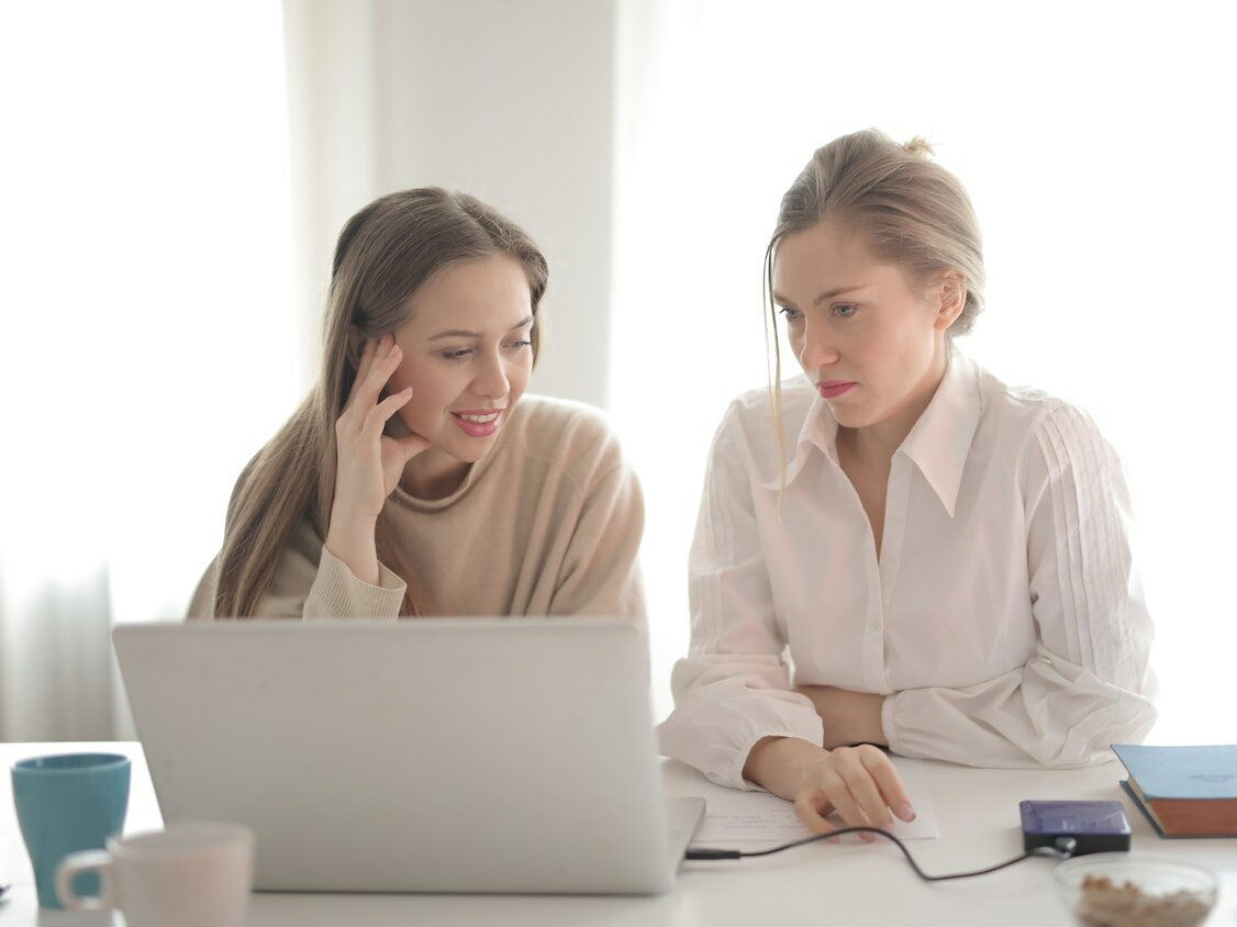 Zwei Frauen sitzen vor einem Laptop